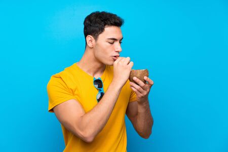 Handsome man over blue background with a coconutの写真素材
