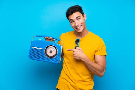Handsome man over blue background holding a radioの写真素材