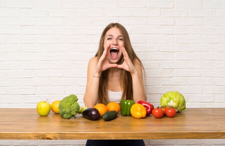 Young woman with many vegetables shouting with mouth wide openの写真素材