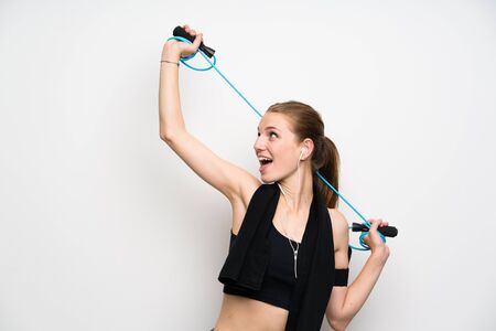 Young sport woman over isolated white background with jumping rope