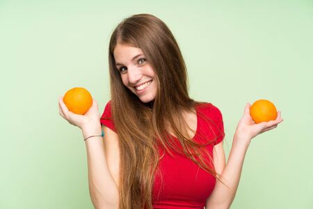 Young woman with long hair holding an orangeの写真素材