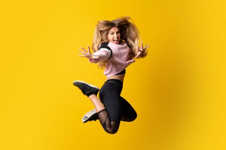 Urban Ballerina dancing over isolated yellow background and jumping