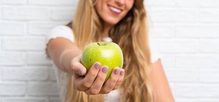 Happy Young blonde woman with an apple