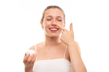 Young blonde woman over isolated white background with moisturizerの写真素材