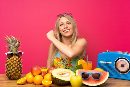Young blonde woman with lots of fruits celebrating a victoryの写真素材