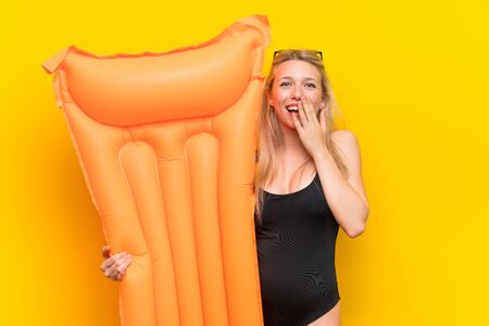 Young woman in swimsuit over yellow background laughingの写真素材
