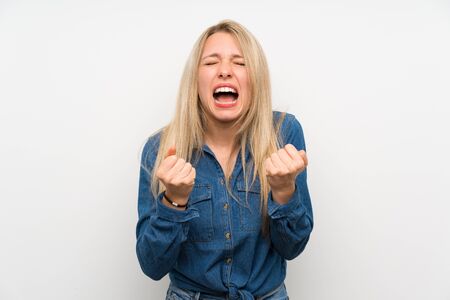 Young blonde woman over isolated white wall frustrated by a bad situationの写真素材