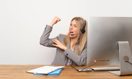 Young woman working with headset making strong gestureの写真素材