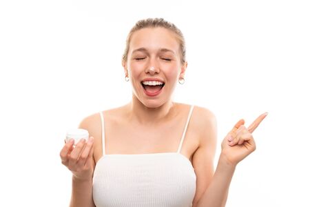 Young blonde woman over isolated white background with moisturizerの写真素材