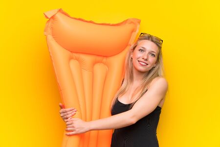 Young woman in swimsuit over yellow background keeping arms crossedの写真素材