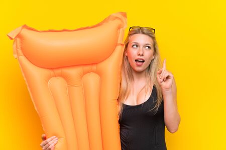 Young woman in swimsuit over yellow background thinking an ideaの写真素材