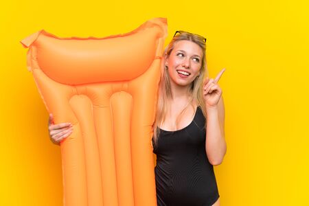 Young woman in swimsuit over yellow background pointing with the index finger a great ideaの写真素材