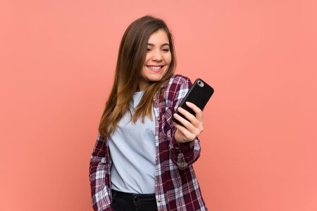 Young girl over pink wall making a selfieの写真素材