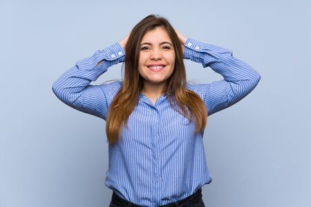 Young girl over isolated blue wall frustrated and takes hands on headの写真素材