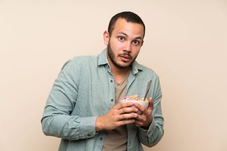 Colombian man with bowl of cereals is a little bit nervous and scaredの写真素材