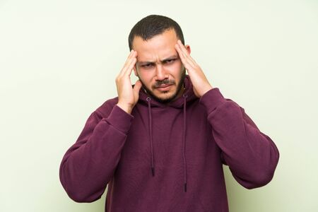 Colombian man with sweatshirt over green wall unhappy and frustrated with something. Negative facial...