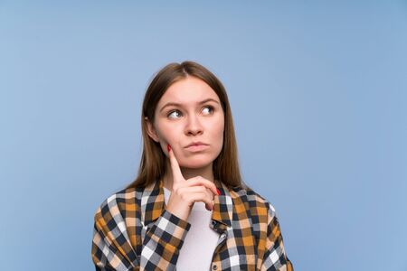 Young woman over blue wall thinking an idea