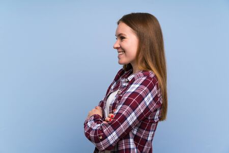Young woman over blue wall standing and looking to the sideの写真素材