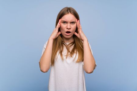 Young woman over blue wall with surprise and shocked facial expressionの写真素材