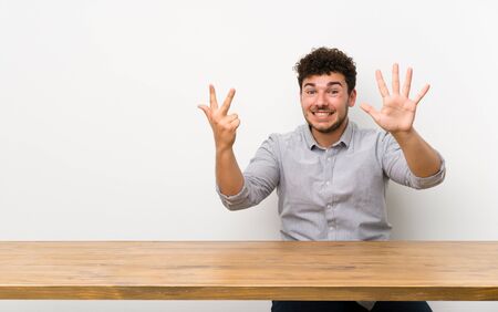 Young man with a table counting eight with fingersの写真素材