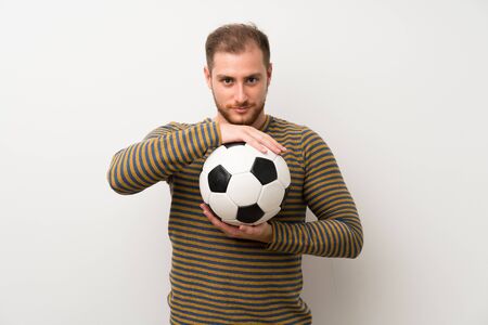 Handsome man over isolated white wall holding a soccer ballの写真素材