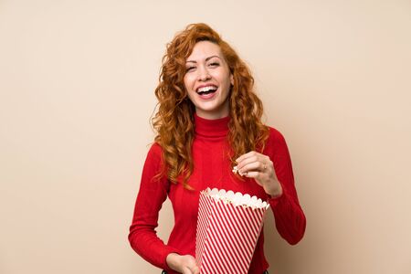 Redhead woman with turtleneck sweater holding a bowl of popcornsの写真素材