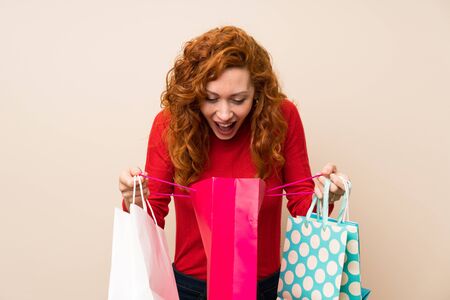 Redhead woman with turtleneck sweater holding a lot of shopping bagsの写真素材