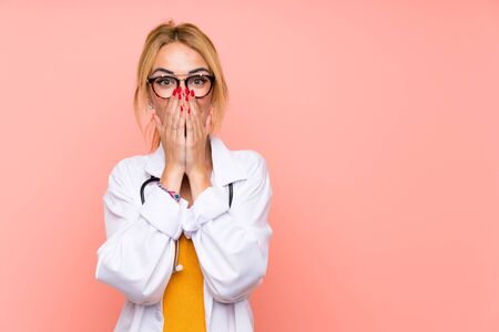 Young blonde doctor woman with surprise facial expressionの写真素材