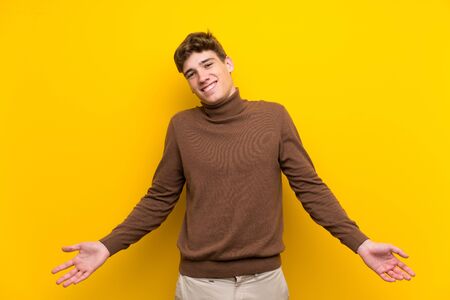 Handsome young man over isolated yellow background smilingの写真素材