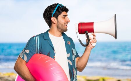 Man in trunks shouting through a megaphone at the beachの写真素材
