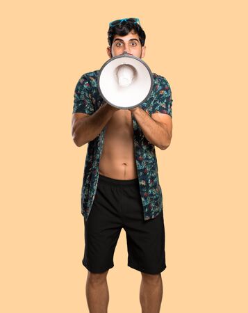 Man in trunks shouting through a megaphone over isolated yellow backgroundの写真素材