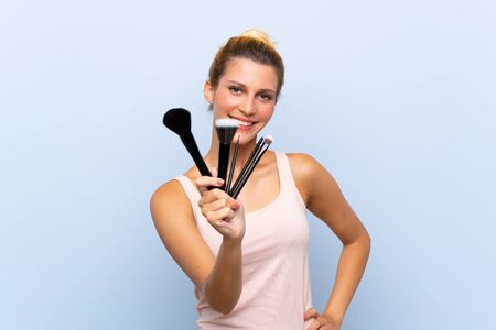 Young blonde woman holding lots of makeup brushの写真素材