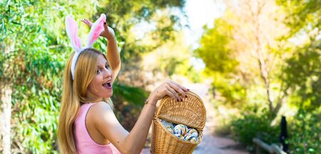 young blonde woman wearing bunny ears and with colorful Easter eggsの写真素材