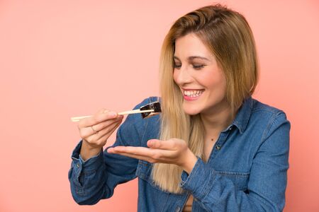 Young blonde woman eating sushiの写真素材