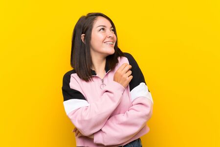 Young Mexican woman over isolated yellow background laughingの写真素材