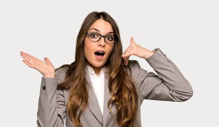 Business woman making phone gesture and doubting over isolated grey backgroundの写真素材