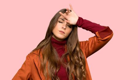 Young woman with coat with tired and sick expression over isolated pink backgroundの写真素材