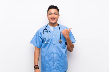 Young surgeon doctor man over isolated white wall pointing to the side to present a productの写真素材