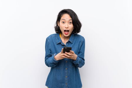 Asian young woman over isolated white background surprised and sending a messageの写真素材