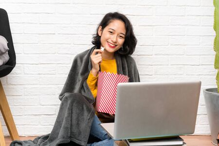 Asian young woman sitting on the floor eating popcornsの写真素材