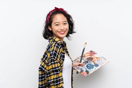 Young artist woman holding a palette over isolated white background smiling a lotの写真素材