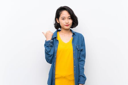 Asian young woman over isolated white background pointing to the side to present a productの写真素材