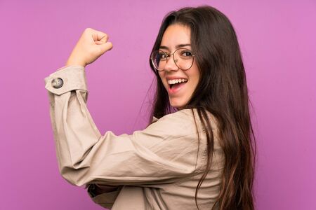 Teenager girl over purple wall making strong gesture