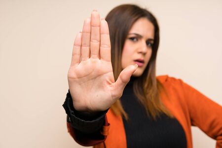 Young woman with coat making stop gesture with her hand