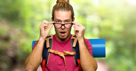 Hiker man with mountain backpacker with glasses and surprised in the mountainの写真素材