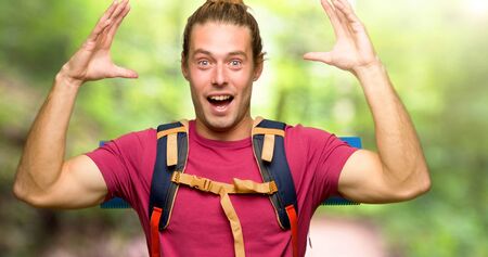 Hiker man with mountain backpacker with surprise and shocked facial expression in the mountainの写真素材