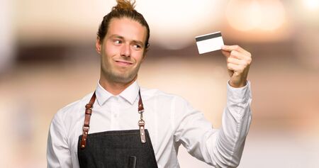 Barber man in an apron taking a credit card without money in a barber shopの写真素材