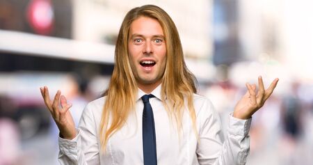 Blond businessman with long hair with surprise and shocked facial expression at outdoorsの写真素材