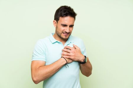 Handsome young man over isolated background having a pain in the heart