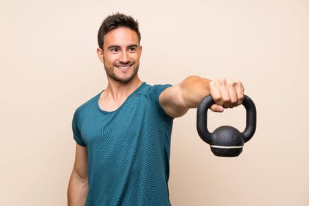 Handsome sport man over isolated background with kettlebellの写真素材